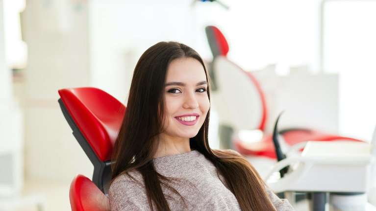 Female with white teeth in a red dental chair in Rehoboth beach, DE
