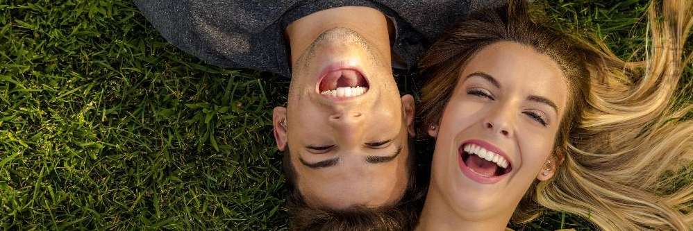 A couple lies on a lush green grassy field