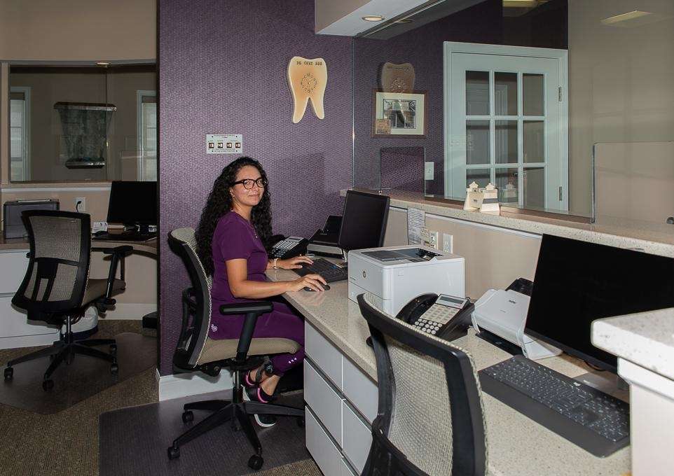 A smiling woman behind the front desk at Rehoboth Beach Dental